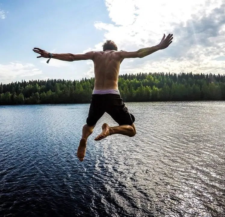 Muscular young man jumping into a lake