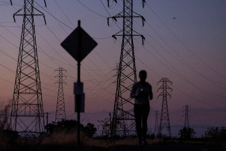 REUTERS/CARLOS BARRIA / 2022
                                A woman jogs by power lines, as California’s grid operator urged the state’s 40 million people to ratchet down the use of electricity in homes and businesses as a wave of extreme heat settled over much of the state, in Mountain View, Calif.