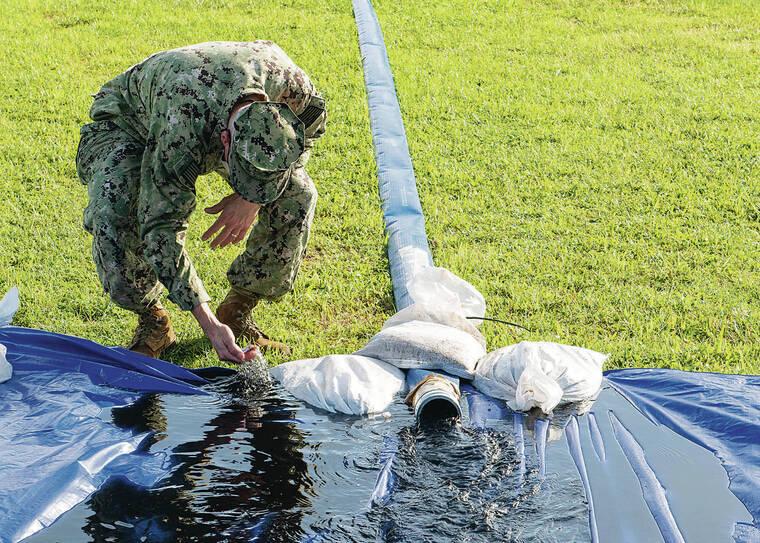 MASS COMMUNICATION SPECIALIST SEAMAN CHRISTOPHER THOMAS / U.S. NAVY / 2021
                                Capt. Randall Harmeyer, Joint Base Pearl Harbor-Hickam public works officer, inspects water flushed through granulated activated carbon filters from the Waiawa Shaft water supply.