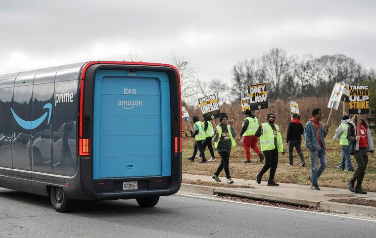 REUTERS/ELIJAH NOUVELAGE
                                An Amazon delivery truck passes people holding signs and marching during a strike by Teamsters union members at an Amazon facility in Alpharetta, Ga., today.